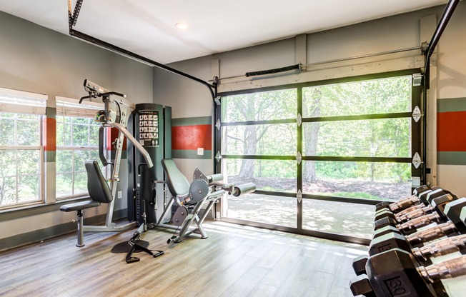 The fitness center at our apartments in Antioch, featuring wood grain floor paneling, free weights, and exercise machines.