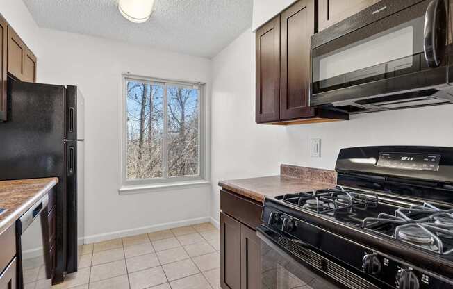 A kitchen with black appliances and brown cabinets.