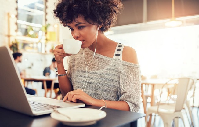 a woman sitting at a table with a laptop and a cup of coffee