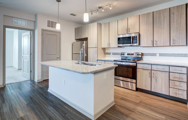 a kitchen with a large island and wooden floors and cabinets