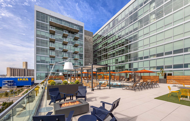 A modern building with a glass facade and a patio with chairs and tables.