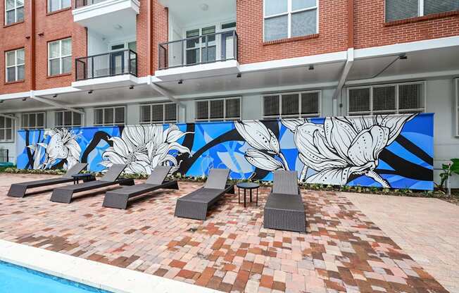 Poolside lounging area with vibrant mural at The Grand at Upper Kirby apartments in Houston, TX