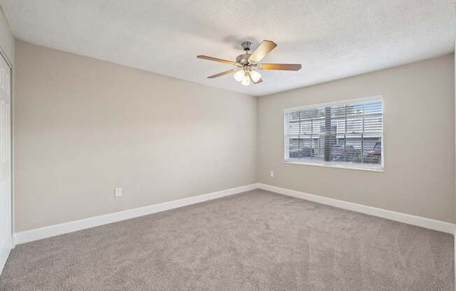 Empty room with a ceiling fan and a window.