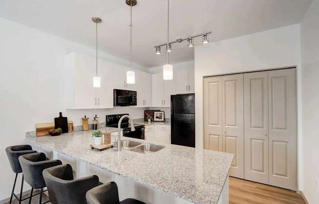 A kitchen with a granite countertop and a black refrigerator.