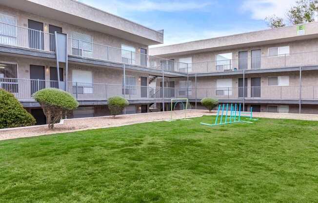 A playground with a slide is in the courtyard of apartment buildings.
