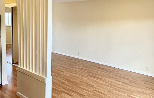 an empty living room with a radiator and hardwood floors