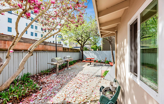 A patio with a bench and a tree with pink flowers.