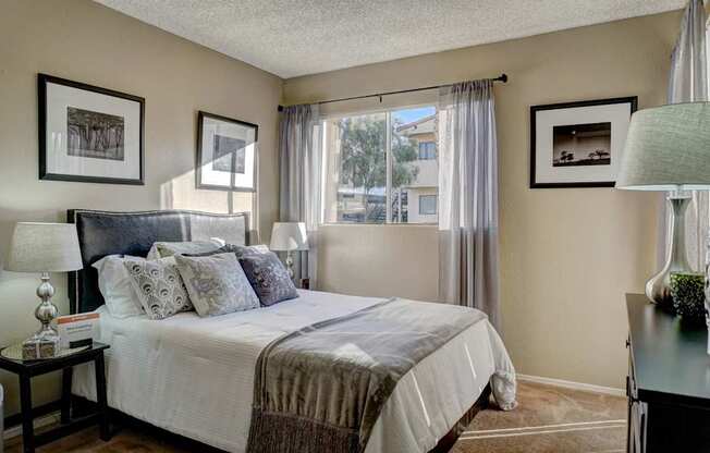 A bedroom with a large bed and a window with curtains.