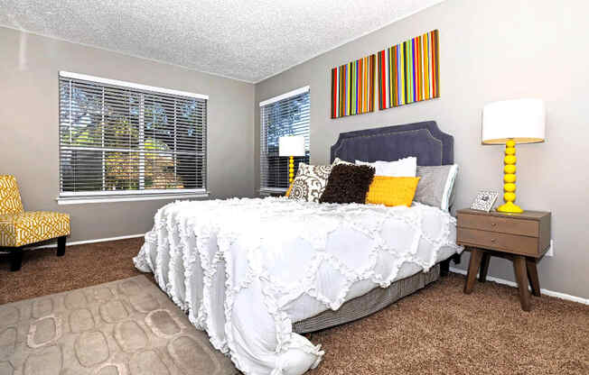 A bedroom with a bed, nightstand, and chair.