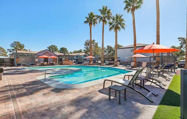 A pool surrounded by palm trees and sun loungers.