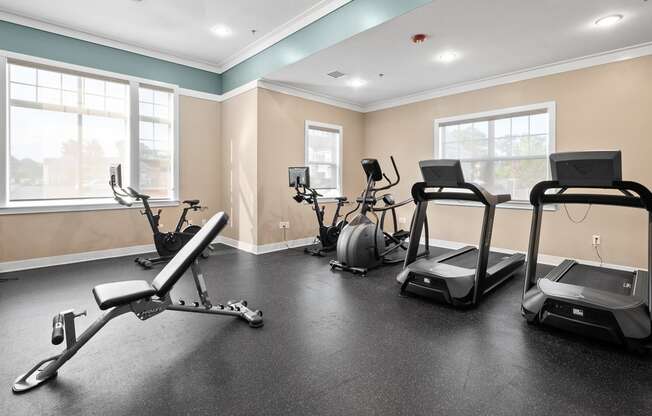 an exercise room with treadmills and weights at the enclave at woodbridge apartments