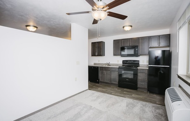 a kitchen with black appliances and a ceiling fan