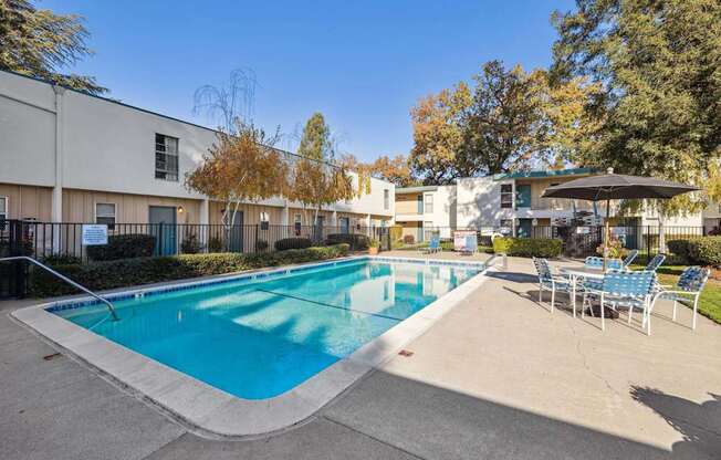 A large outdoor swimming pool surrounded by chairs and trees.