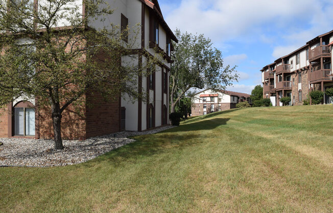 a large building with a grass lawn and trees at Seville Apartments, Michigan