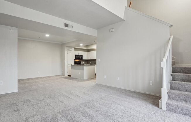A spacious living room with a staircase on the right side.