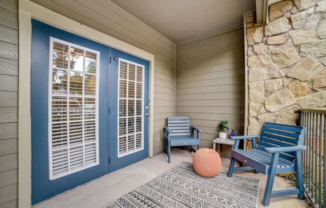 front porch with two chairs and a table with a potted plant