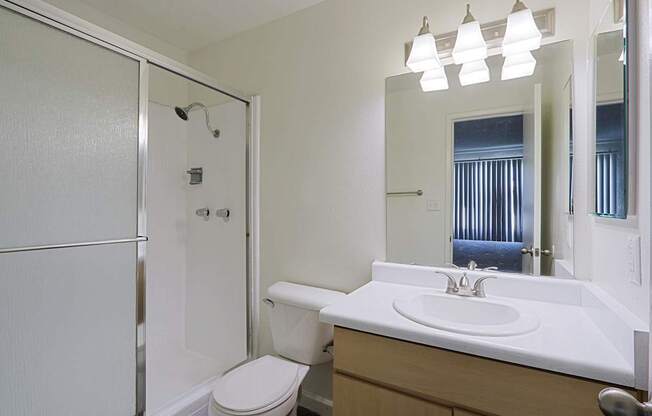 A white bathroom with a toilet, sink, and shower.