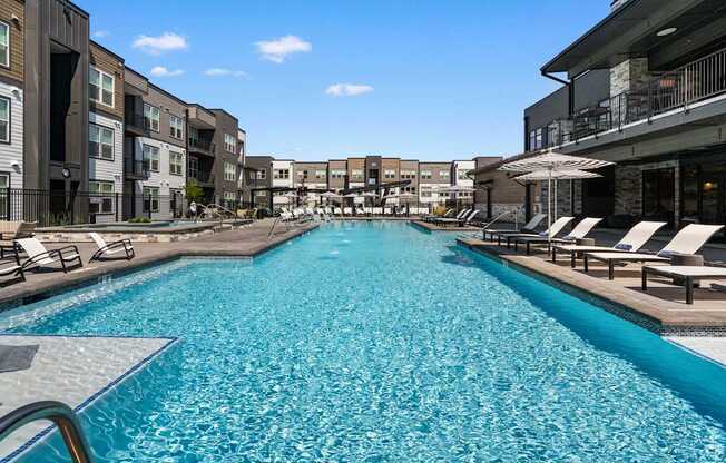 A large swimming pool in a resort with sun loungers.