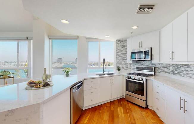 A modern kitchen with white cabinets and a marble countertop at Esprit Marina del Rey, 90292