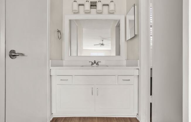 a bathroom with white cabinets and a sink and a mirror