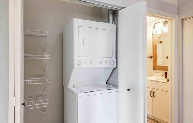 Closet with stacked in unit washer and dryer with shelving and storage.