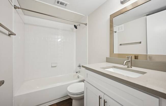 a bathroom with bright lights and white cabinets at Woodlands of Plano in Plano, TX