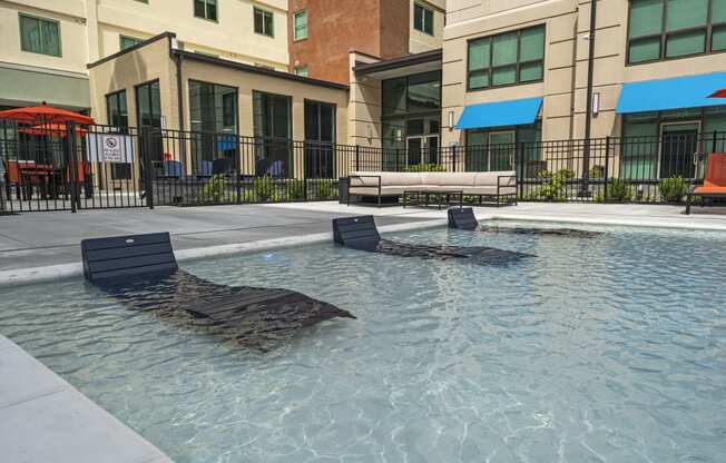 a pool with lounge chairs and umbrellas in front of a building  at The Icon, Richmond, 23230