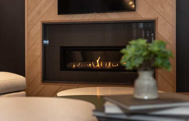 a fireplace with wood paneling and a vase of flowers on a coffee table at The Bend Arbordale, Virginia, 23188