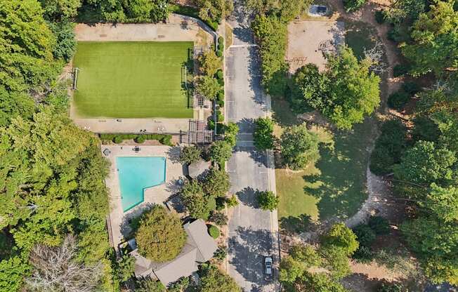 A large green field with a pool and a house.