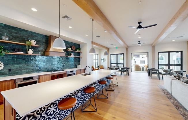A long white table with chairs is in the middle of a room with a ceiling fan at The Villas at Anacapa Canyon, Camarillo, 93012