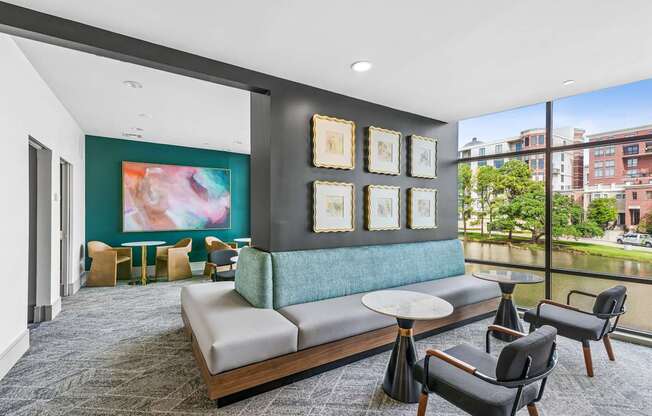 A living room with a grey sofa, a round table and a painting on the wall.