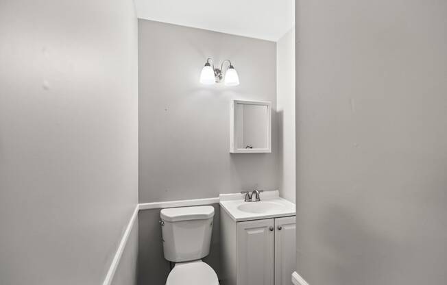 A bathroom with a toilet, sink, and medicine cabinet.