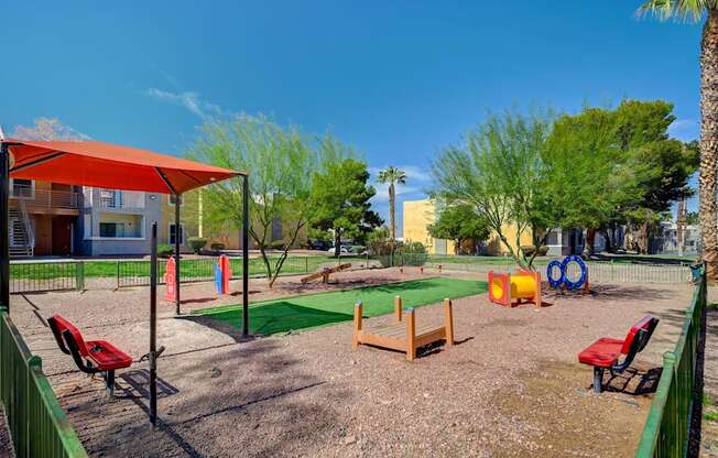 A playground with a red canopy and a green fence.