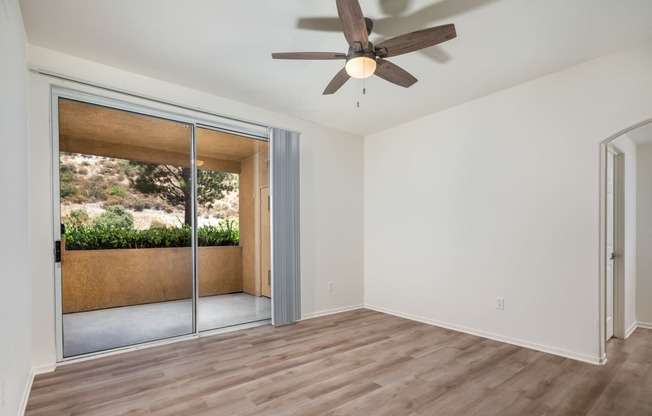 an empty living room with a ceiling fan and sliding glass doors