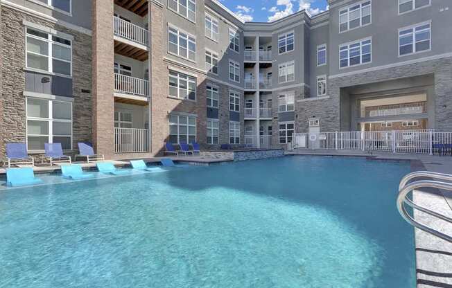 A large swimming pool in front of a multi-story residential building.