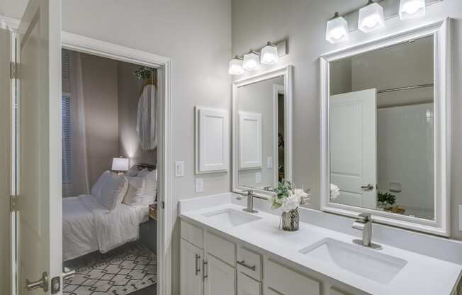 a bathroom with a sink and three mirrors and a bed