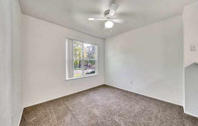 an empty room with a window and a ceiling fan