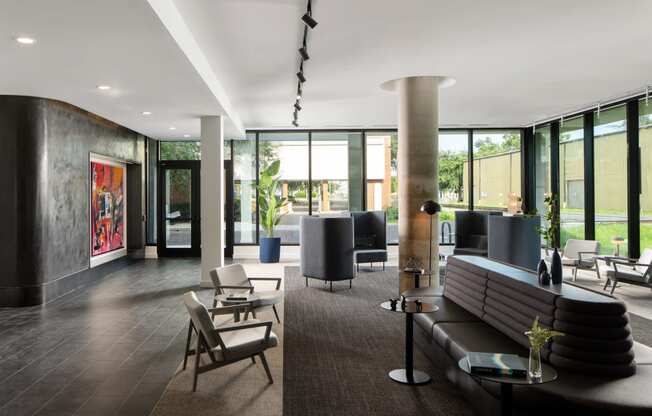 a living room with a couch and chairs and a large wall of windows