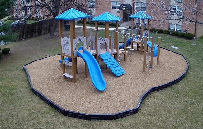 a playground with a blue slide and playset in a yard