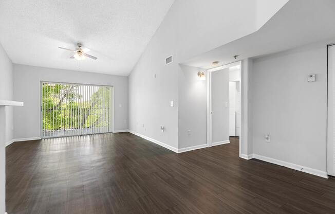 A room with a slanted ceiling and a window with a view of a fence.
