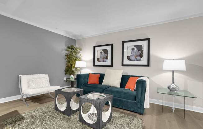 A living room with a green couch, a white chair, and a glass table.