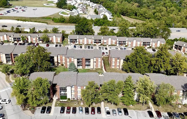 an aerial view of an apartment complex with parking lot and trees