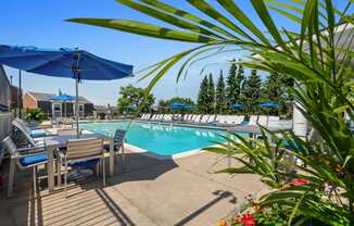 our resort style swimming pool is surrounded by patio furniture and umbrellas