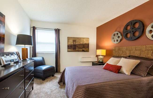 A bedroom with a bed, dresser, and window.