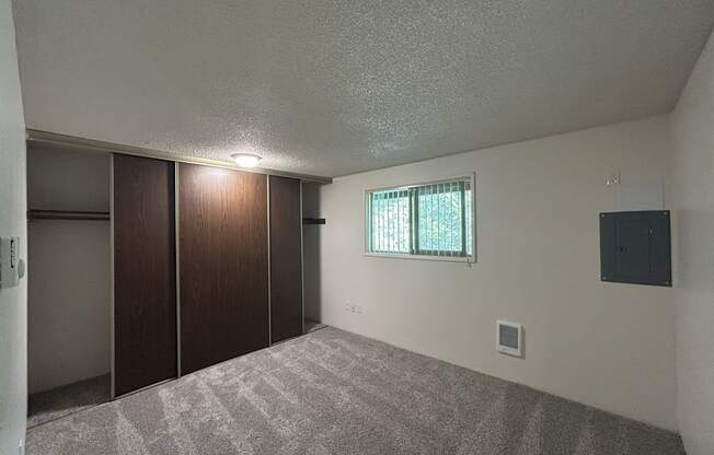 A room with a carpeted floor and a window with blinds.