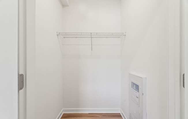 A white wall with a shelf and a door.