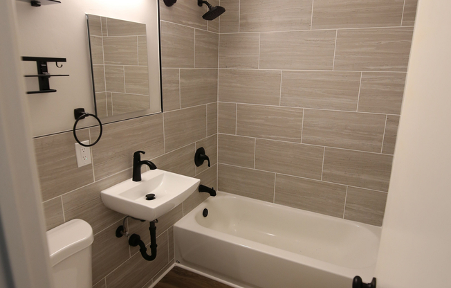 Modern bathroom with sleek fixtures, elegant tile work, and rich wood flooring, offering a stylish and functional space.