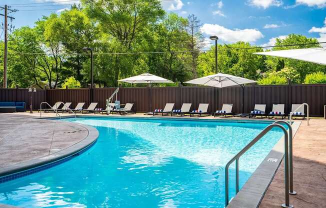 a swimming pool with chairs and umbrellas. Circle Pines, MN Lexington Lofts