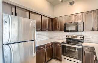 A kitchen with a stainless steel refrigerator, microwave, oven, and cabinets with quartz countertops.