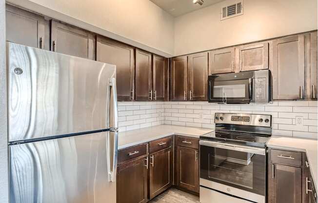 A kitchen with a stainless steel refrigerator, microwave, oven, and cabinets with quartz countertops.